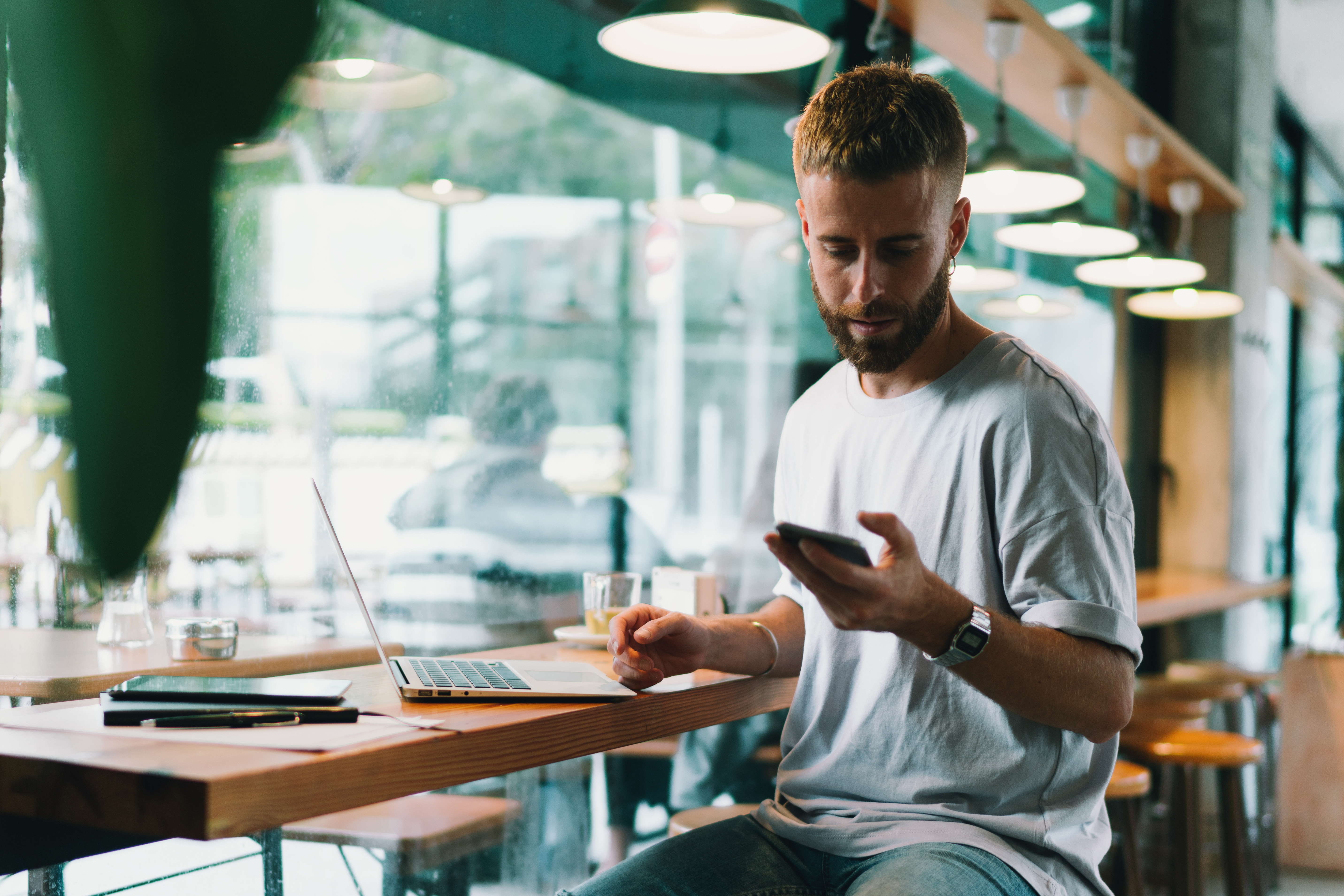 reasons to switch banks; image of young man at cafe on phone doing online banking