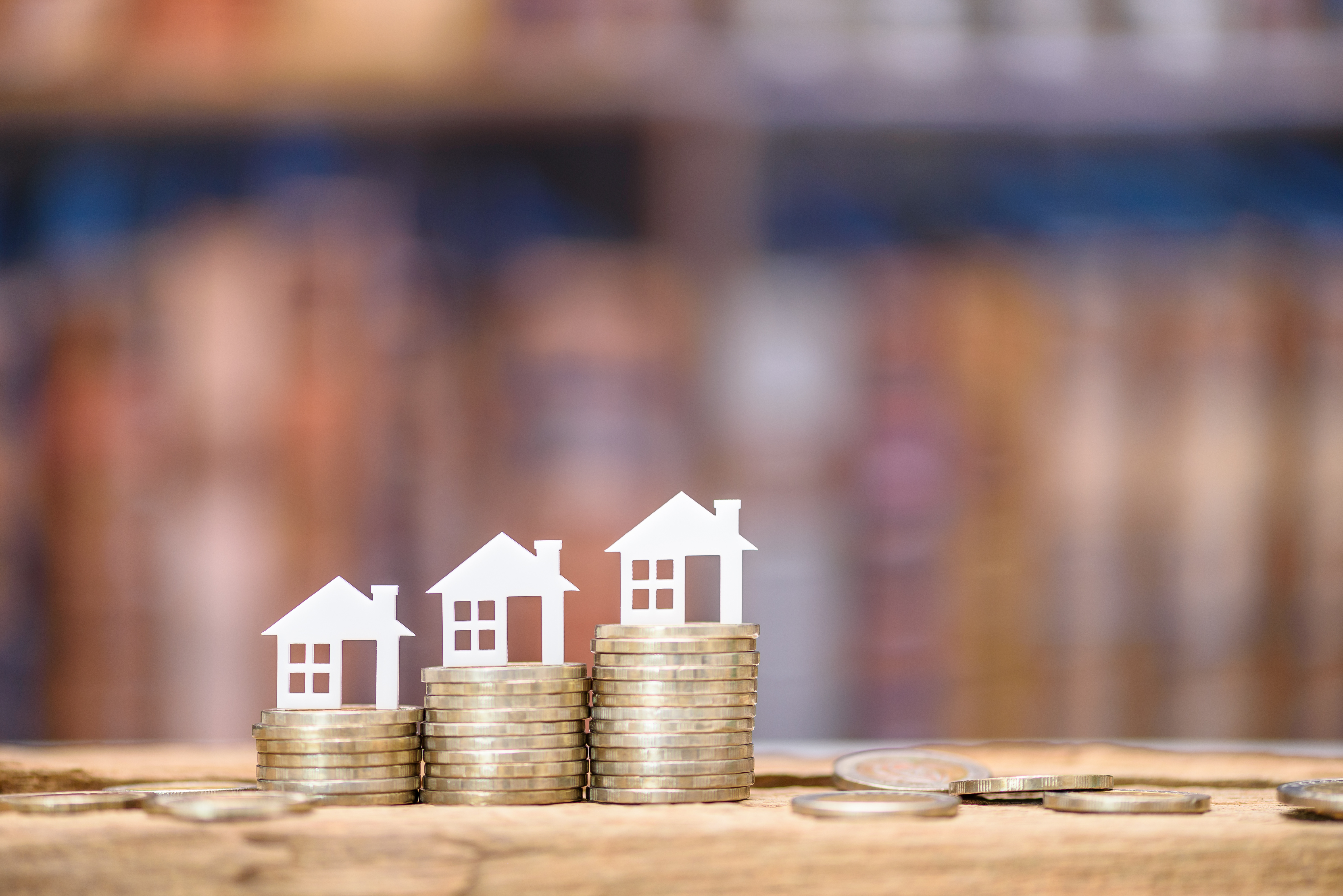 three stacks of coins with small model white homes on them. home equity line of credit heloc vs. home equity loan