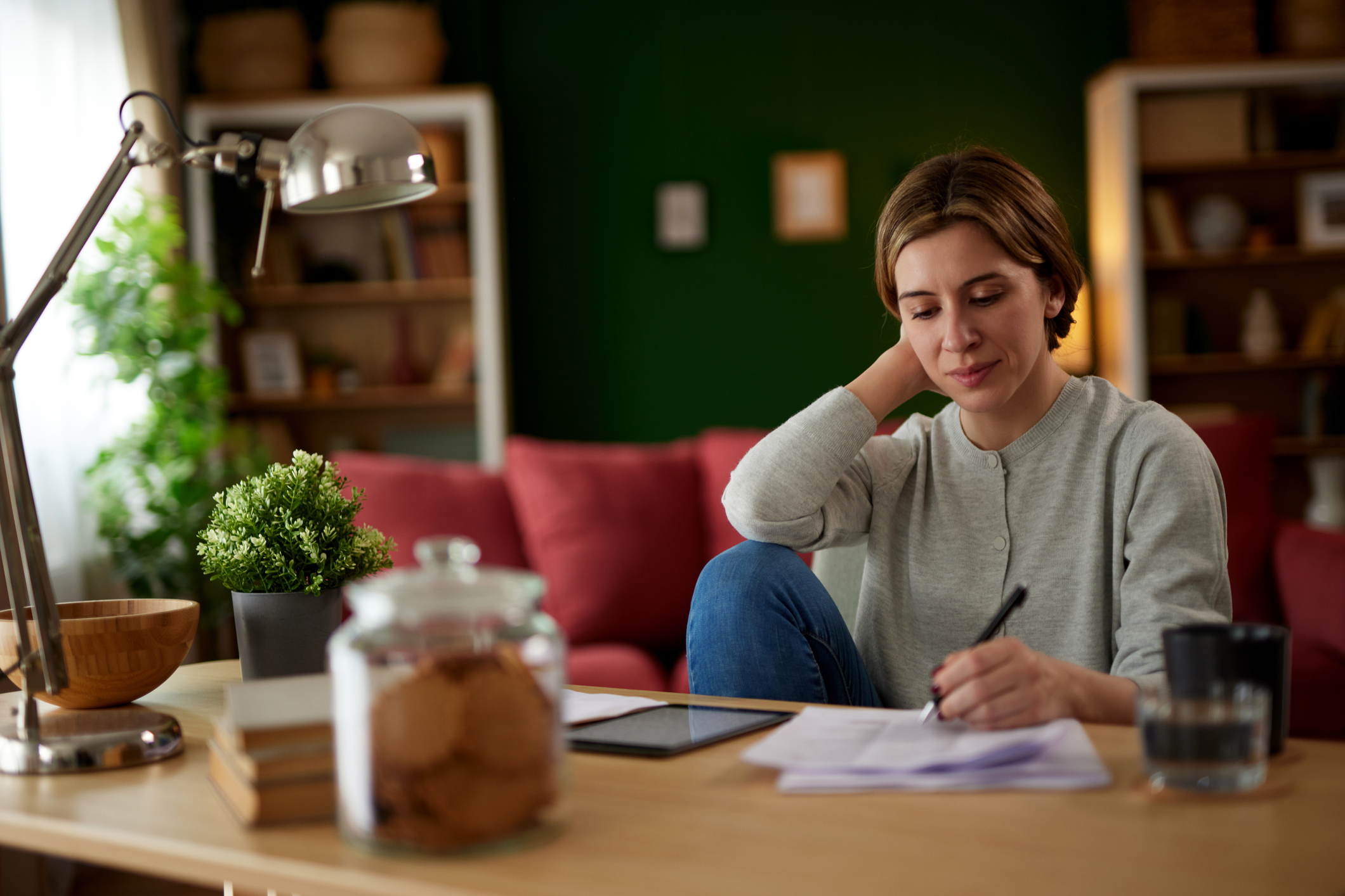 does opening a checking account affect my credit score; image of woman with short hair  at desk with pen and paper